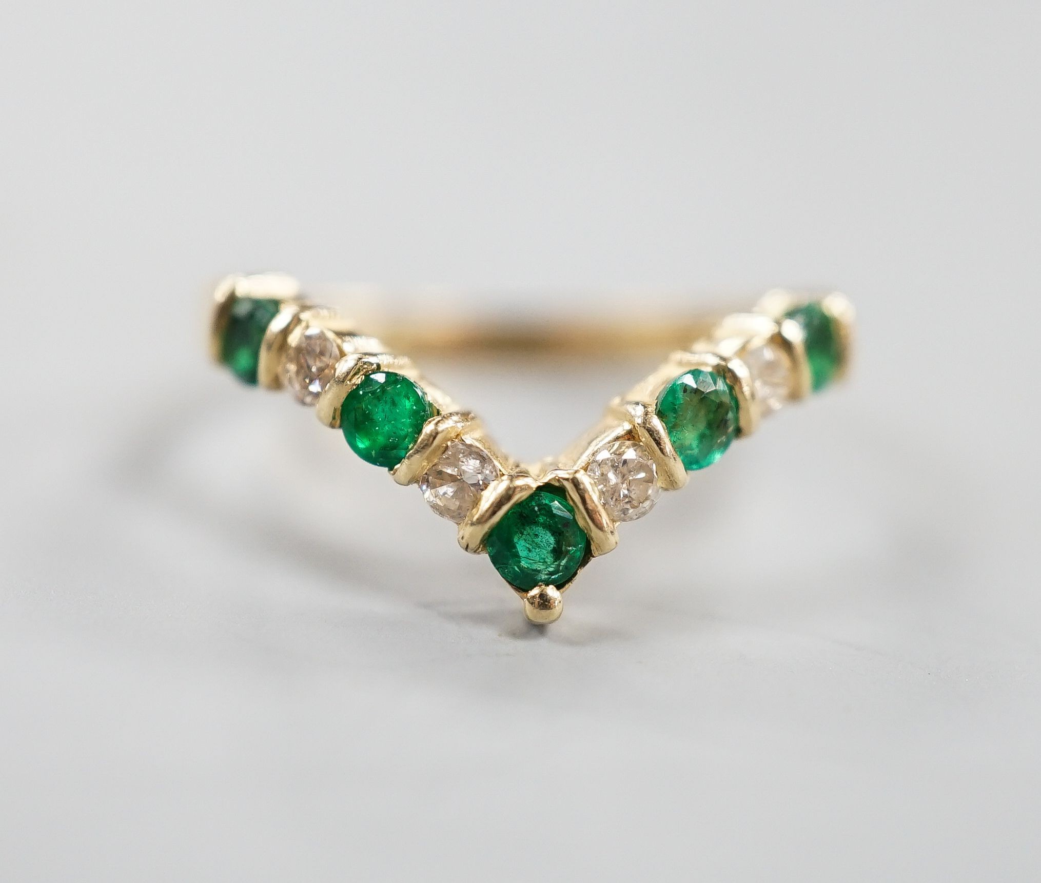 A modern 14k yellow metal, five stone emerald and four stone diamond set wishbone ring, size M, gross 2.3 grams.